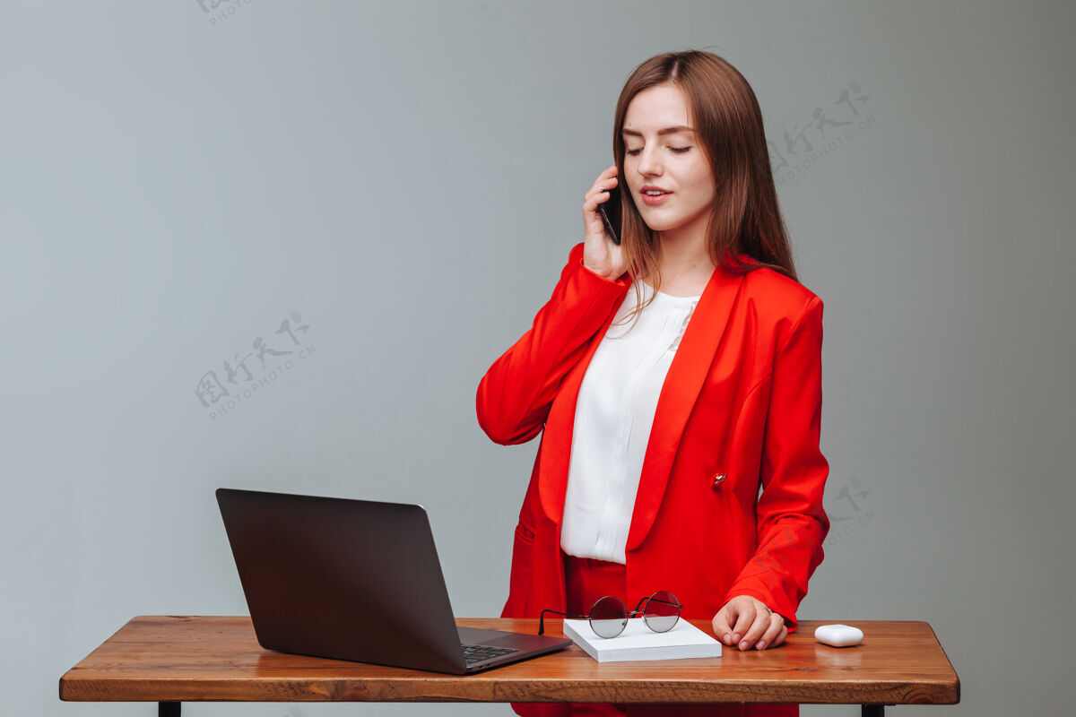 麦克风穿着红色夹克的女孩一边用笔记本电脑一边打电话显示器西装工作