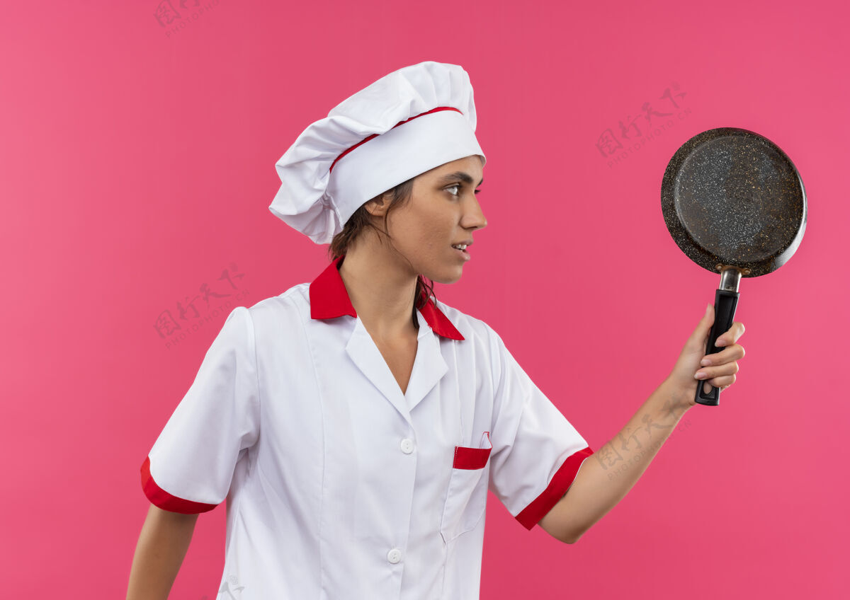平底锅站在剖面图年轻的女厨师穿着厨师制服拿着煎锅与复制空间厨师厨师制服