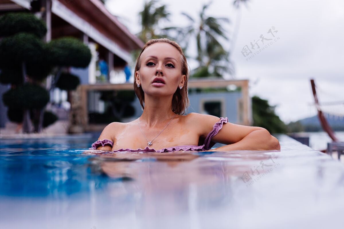 游泳穿着比基尼的白种女人在蓝色游泳池的时尚写真 在coudydaynaturallight度假休闲比基尼热带