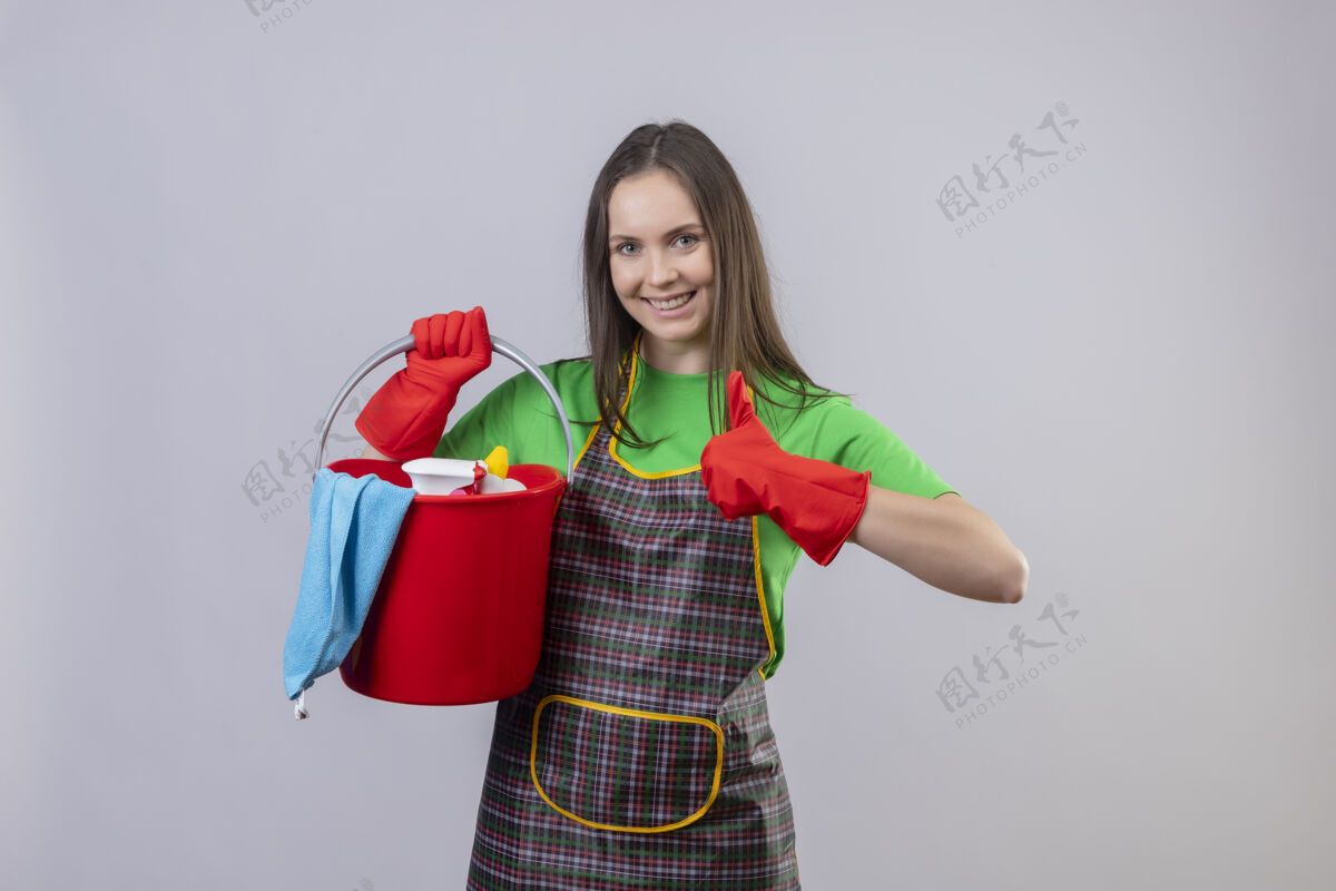 戴着微笑着清洗穿着制服 戴着红手套 拿着清洁工具的年轻女孩 在孤立的白色背景上竖起大拇指年轻拿着白