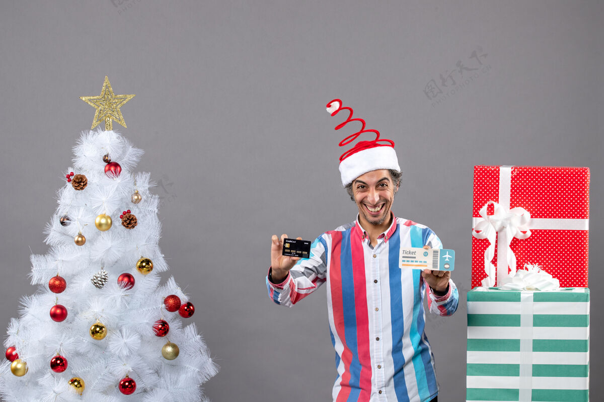 卡片前视图快乐的人拿着圣诞树周围的卡片和旅行票帽子人人