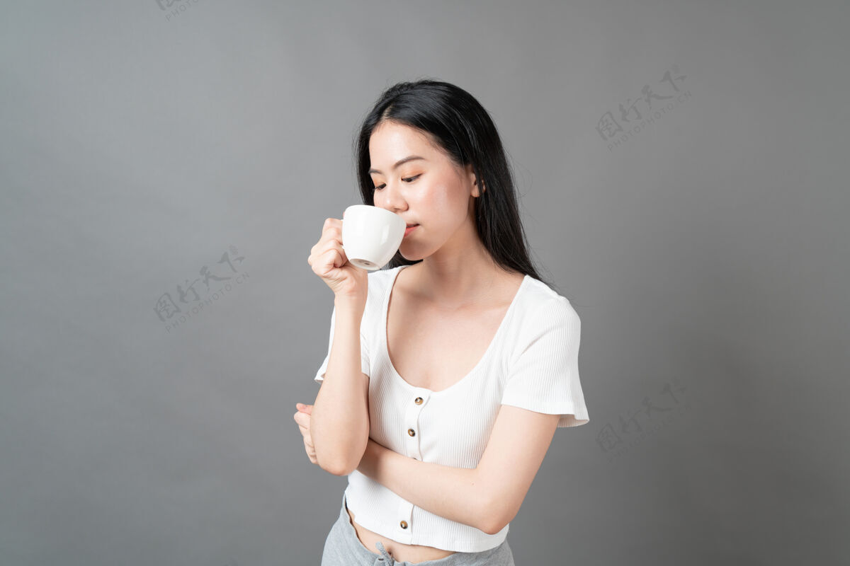 可爱一个年轻的亚洲女人 脸上洋溢着幸福 手里拿着咖啡杯微笑女人女性