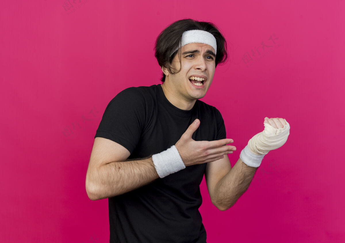粉色年轻的运动型男子穿着运动服 戴着头巾 胳膊指着缠着绷带的手腕 感到疼痛手臂运动男人