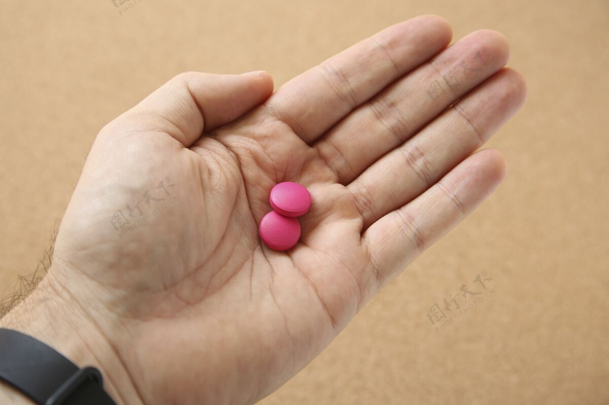 病人高角度拍摄的一个人的手与两个粉红色的药丸粉红色角度治疗高角度