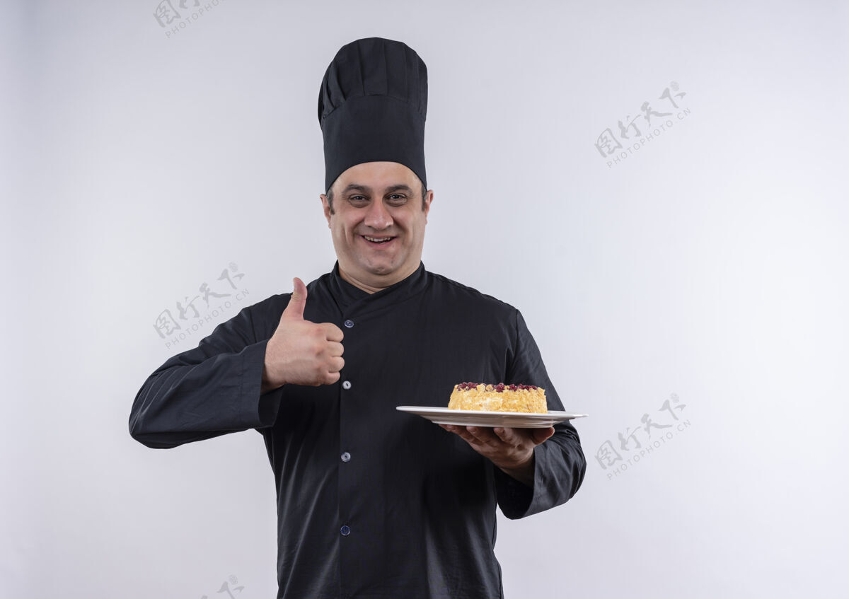 蛋糕一位身着厨师制服的中年男厨师拿着盘子上的蛋糕 大拇指竖立在隔离的白色墙壁上 上面留有复印空间中年厨师制服