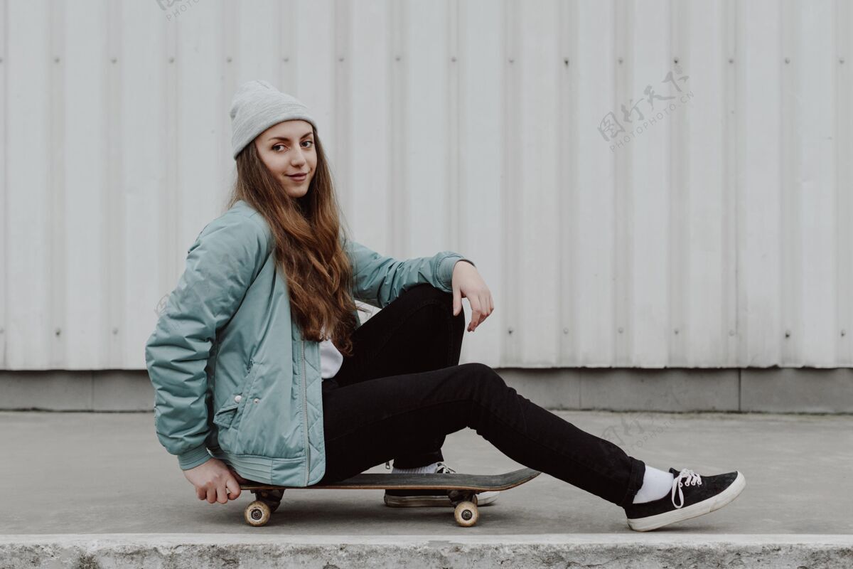 滑板坐在户外滑板旁边的女滑板手城市滑板女人