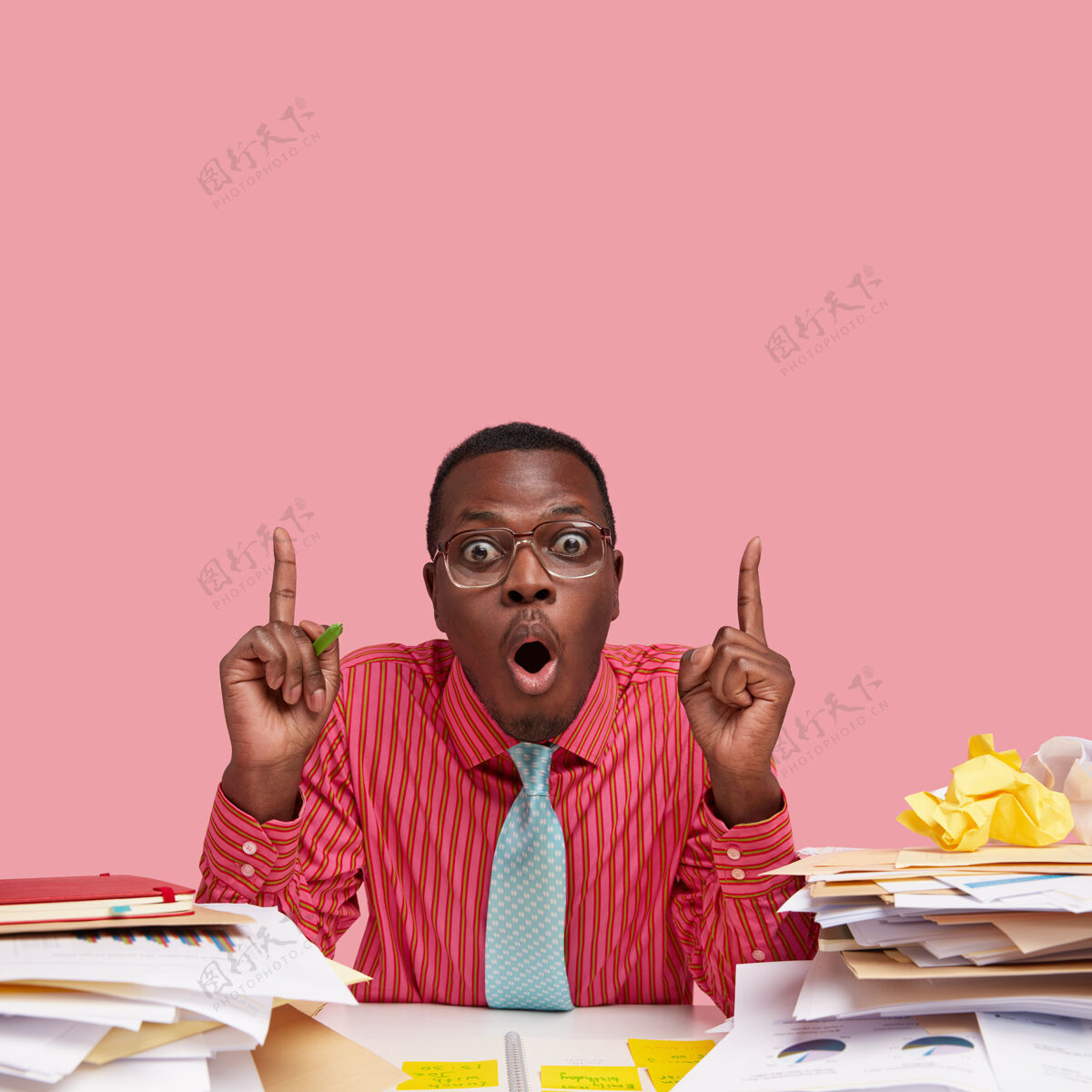 向上惊呆了的年轻黑人经理有一双窃听的眼睛 穿着粉色的正式衬衫和领带 用食指向上指男性经理办公室