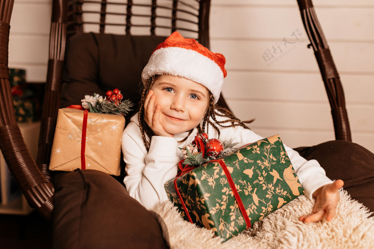 生活快乐的小女孩戴着圣诞帽摆圣诞礼物愿望客厅礼物